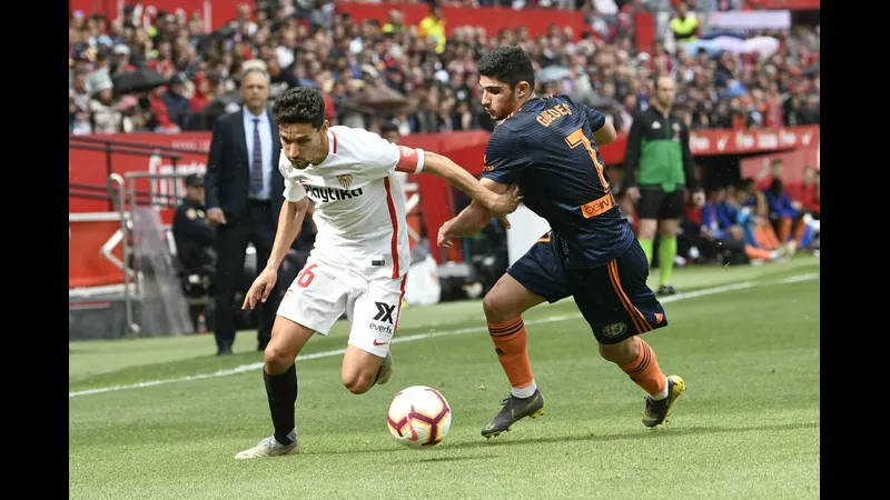 Cầu thủ của Valencia đang nỗ lực vượt qua sự chặn đứng của hậu vệ Sevilla Cầu thủ của Valencia đang nỗ lực vượt qua sự chặn đứng của hậu vệ Sevilla